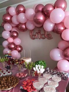 a table topped with lots of desserts and pink balloons hanging over the top of it