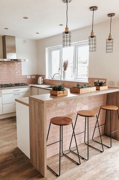 three stools are sitting at the bar in this modern kitchen with pink tiles on the walls