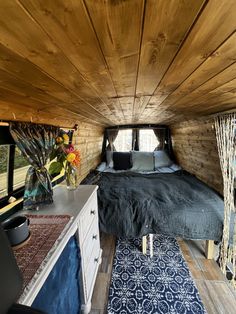 the interior of a small bedroom with wood paneling and blue rugs on the floor