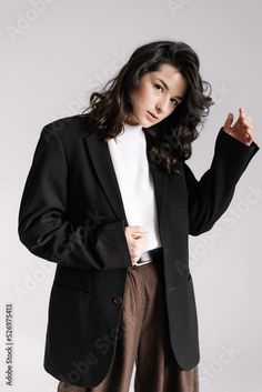 a woman in a black blazer and pants posing for the camera with her hands on her hips