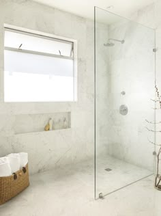 a bathroom with a glass shower door and white marble walls