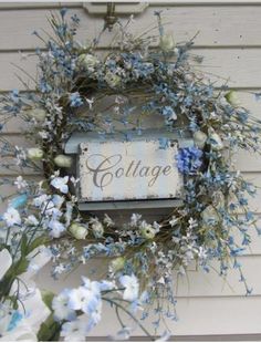 a blue and white wreath hanging on the side of a house with a sign that says cottage