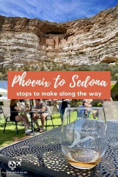 a glass of wine sitting on top of a table in front of a rock formation