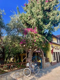 a bike parked in front of a building with flowers on it's tree branches