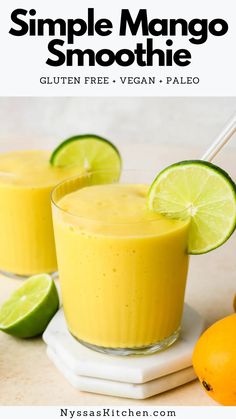 two glasses filled with mango smoothie on top of a white plate next to limes