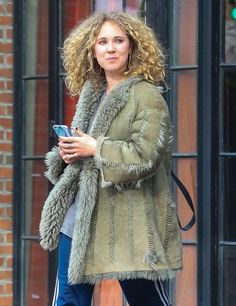 a woman is walking down the street with her cell phone