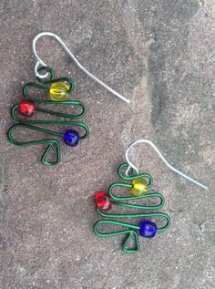 a pair of earrings made out of wire and glass beads sitting on top of a rock