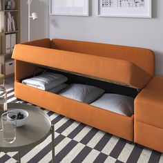 an orange couch with pillows underneath it in a living room