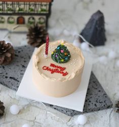 a birthday cake sitting on top of a table next to pine cones and christmas decorations