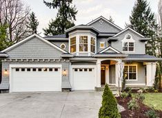 a large house with two garages in front of it and trees around the yard