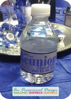 a bottle of water sitting on top of a blue table cloth covered table with plates and silverware