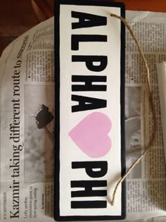 a sign that says aloha phih with a pink heart on it sitting on top of a newspaper