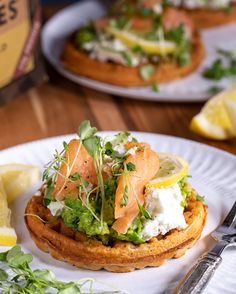 a white plate topped with food on top of a wooden table next to lemon wedges