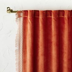 an orange curtain hanging on the side of a white wall next to a pair of scissors