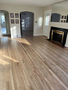 an empty living room with hard wood floors and white walls in the background is a fireplace