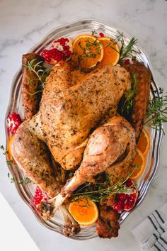 a roasted turkey on a platter with oranges and cranberry garnish