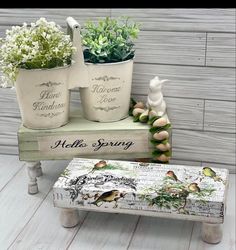 three potted plants sitting on top of a wooden bench next to another planter