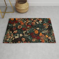 an area rug with flowers on it next to a basket and plant in the corner