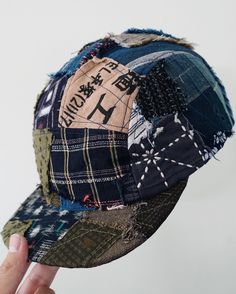 a person holding up a baseball cap made out of old jeans and other fabric material