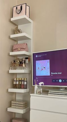 a flat screen tv sitting on top of a white shelf