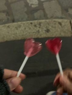 two candy lollipops being held by someone's hand on the street