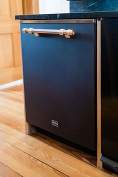 a black dishwasher sitting on top of a wooden floor