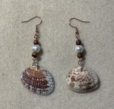 two seashells with pearls are hanging from earrings