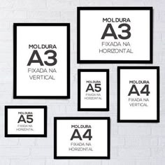 four black and white framed posters on a brick wall with the names of different cities