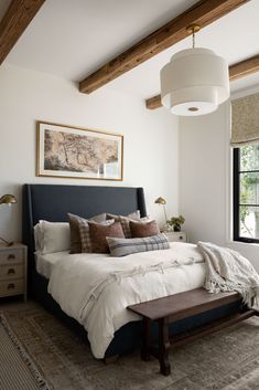 a large bed sitting under a window next to a wooden bench in a living room