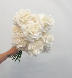 a bouquet of white flowers being held by someone's hand on a white background