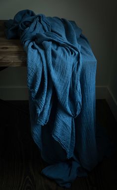 a blue blanket sitting on top of a wooden table next to a window in a dark room