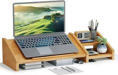 an open laptop computer sitting on top of a wooden desk next to a plant and other office supplies