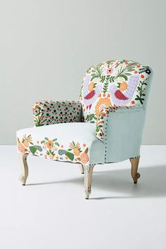 an upholstered chair with flowers and birds on the back, against a white background