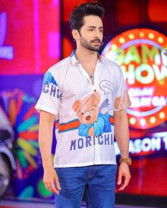 a man standing in front of a neon sign with a teddy bear on his shirt