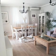 a living room filled with furniture next to a dining room table and white chairs in front of a window