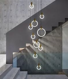 an artistic light fixture hangs from the ceiling above some stairs with concrete steps and handrails