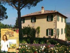 an image of a woman standing in front of a house that is surrounded by flowers