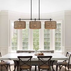 a dining room table with four chairs and a bench in front of two windows that look out onto the woods