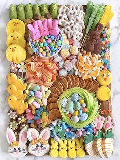 an assortment of cookies and candies are arranged on a marble slab top with easter decorations