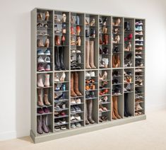 a large closet filled with lots of different types of shoes and boots on shelves next to a white wall