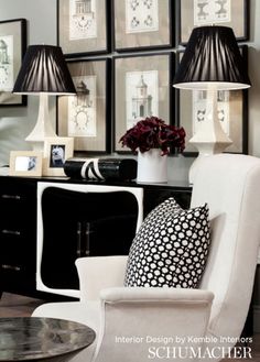 a black and white living room with pictures on the wall, two lamps and a chair