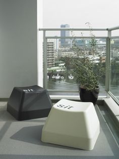 a plant in a black pot sitting on top of a window sill next to a white chair