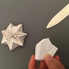 a hand holding some paper next to an origami star