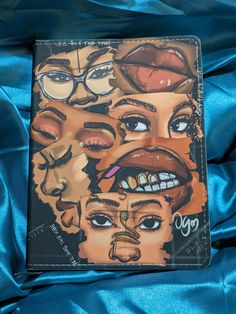 a book with pictures of people's faces on the front and back cover, sitting on a blue satin surface