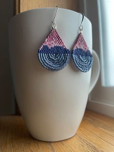 a pair of blue and pink earrings sitting on top of a white vase