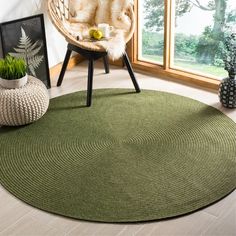 a green rug in a room with a chair and potted plant