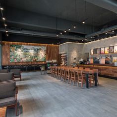 the interior of a restaurant with wooden tables, chairs and artwork on the back wall