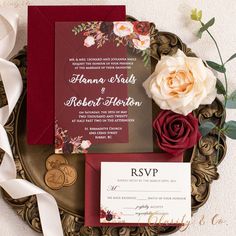 the wedding stationery is laid out on a gold plate with flowers and ribbons around it