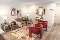 A living room with modern red velvet chairs, a colorful rug, beige couch and abstract art on the wall. Playful Style, Mix Style