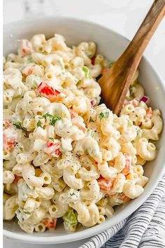 a white bowl filled with macaroni salad and a wooden spoon